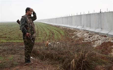 A YPG fighter stands near a wall constructed by Turkey on the border with the Kurdish enclave, Rojava, north of Syria. File Photo: AFP