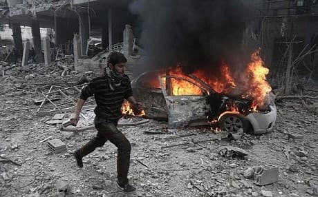 A Syrian man runs past a burning vehicle following reported bombardment by Syrian and Russian forces in the rebel-held town of Hamouria, in the Eastern Ghouta, on January 6, 2018. Photo: AFP / Abdulmonam Eassa 