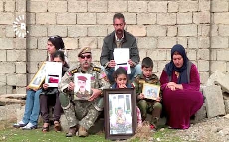 Hassan Mohammed Hashim's family members hold his photograph, demanding the KRG, Iraqi government and international bodies help free their son, allegedly held captive by the Iraqi government. Photo: Rudaw video 