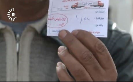 A truck driver who has been charged by one of the five illegal checkpoints shows the receipt of his payment to a Rudaw camera
