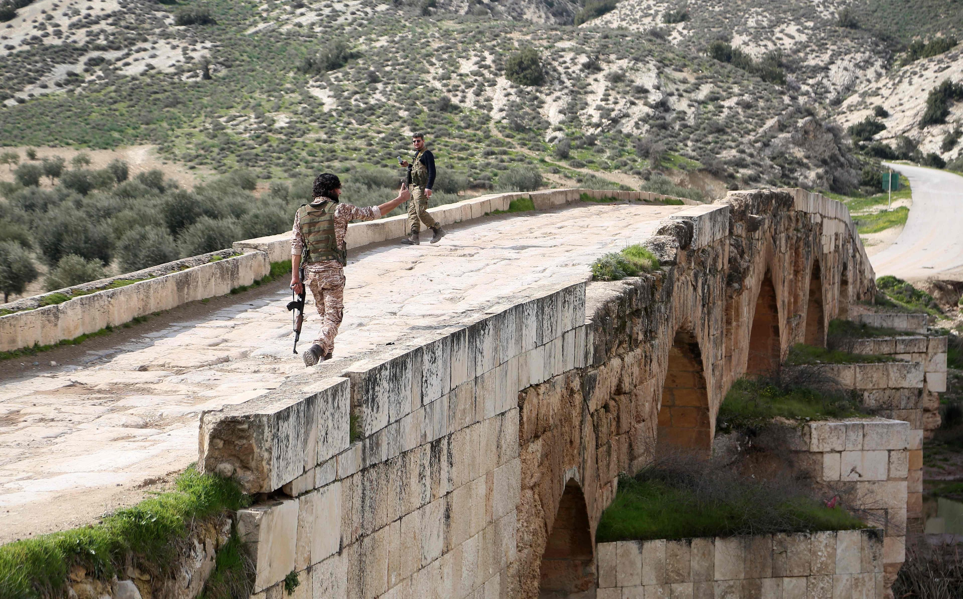 Turkish-backed Syrian fighters walk across the Roman bridge in the archaeological site of Cyrrhus, or Nabi Huri, northeast of Afrin city, after taking control of it from the YPG on Friday. Photo: Nazeer al-Khatib/AFP