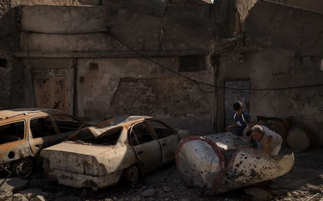 A man and his grandson remove debris from the street in front of their house in Mosul. Photo: AP