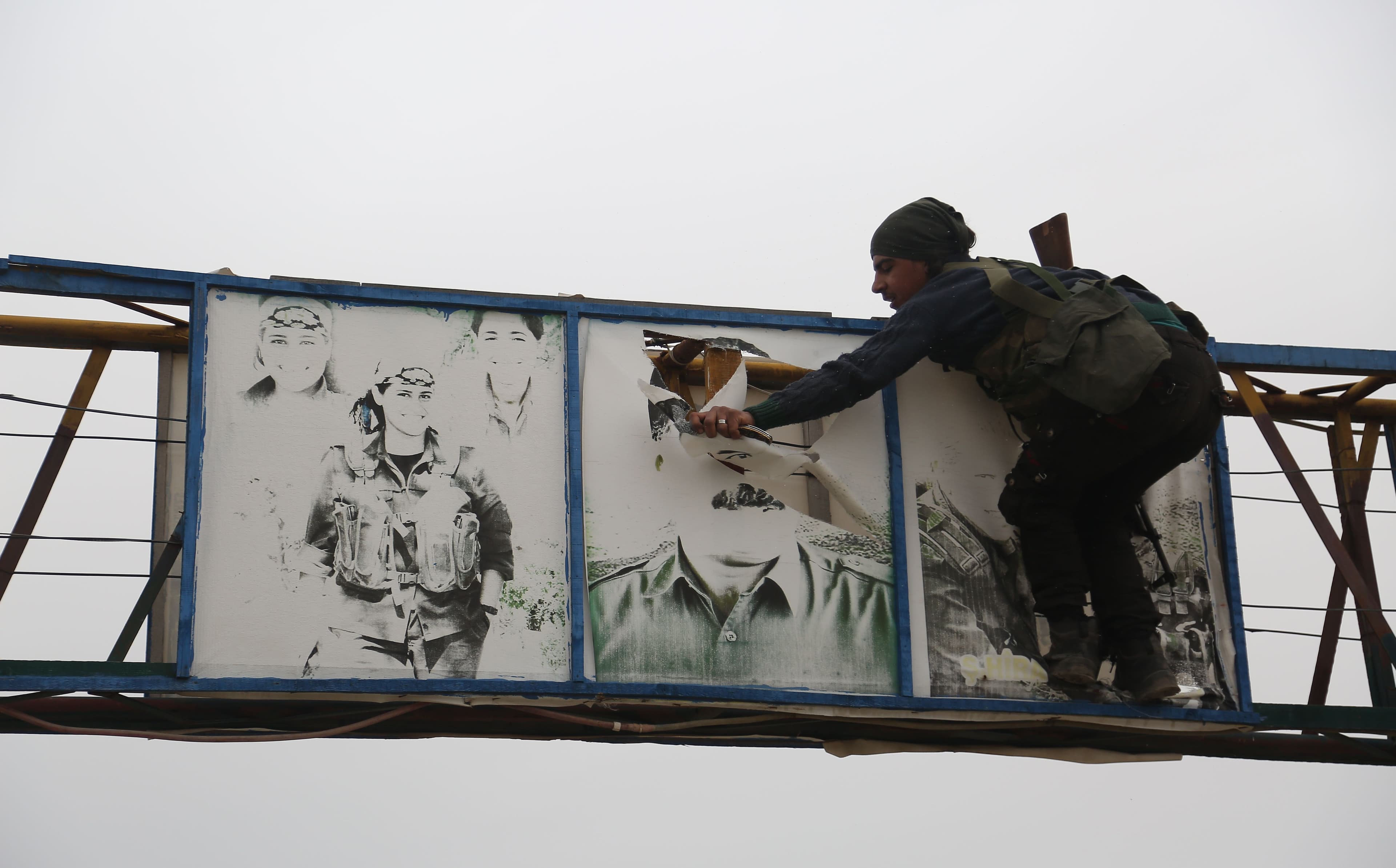 A Turkish-backed Syrian fighter tears down a picture of Abdullah Ocalan in the Hallubi area, north of Afrin, on Thursday. Photo: Nazeer al-Khatib/AFP