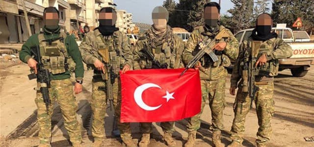 Fighters in Afrin carrying Western-made rifles hold the Turkish flag on March 18, 2018. Photo: DHA TV