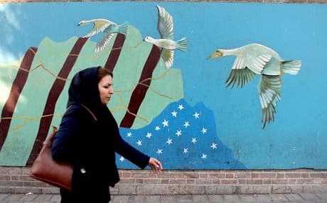 A woman walks past a mural on the wall of the former US embassy in Tehran. File photo: Atta Kenare/AFP