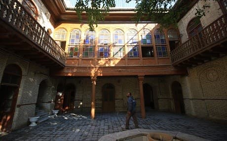 An Iraqi man walks in the courtyard of an old building with traditional "shanasheel", finely crafted bay windows complete with intricate wooden latticework and ornate stained glass which allow inhabitants to see outside without being seen, in the southern city of Basra on December 18, 2017. Photo: Haidar Mohammed Ali | AFP