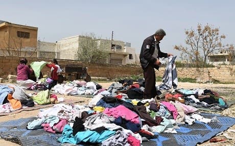 People displaced from Afrin sort through clothing donations in Tal Rifaat this week. Photo: George Ourfalian/AFP