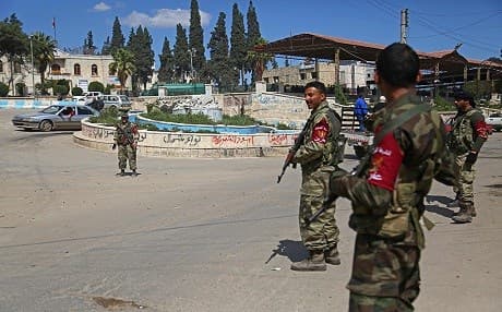 Men with guns patrol the streets in Afrin wearing armbands that say police on April 3, 2018. Photo: Nazeer al-Khatib | AFP