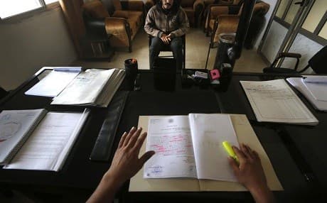A Syrian former ISIS member sits opposite a judging panel in a courtroom in Qamishli in April. Photo: Hussein Malla/AP