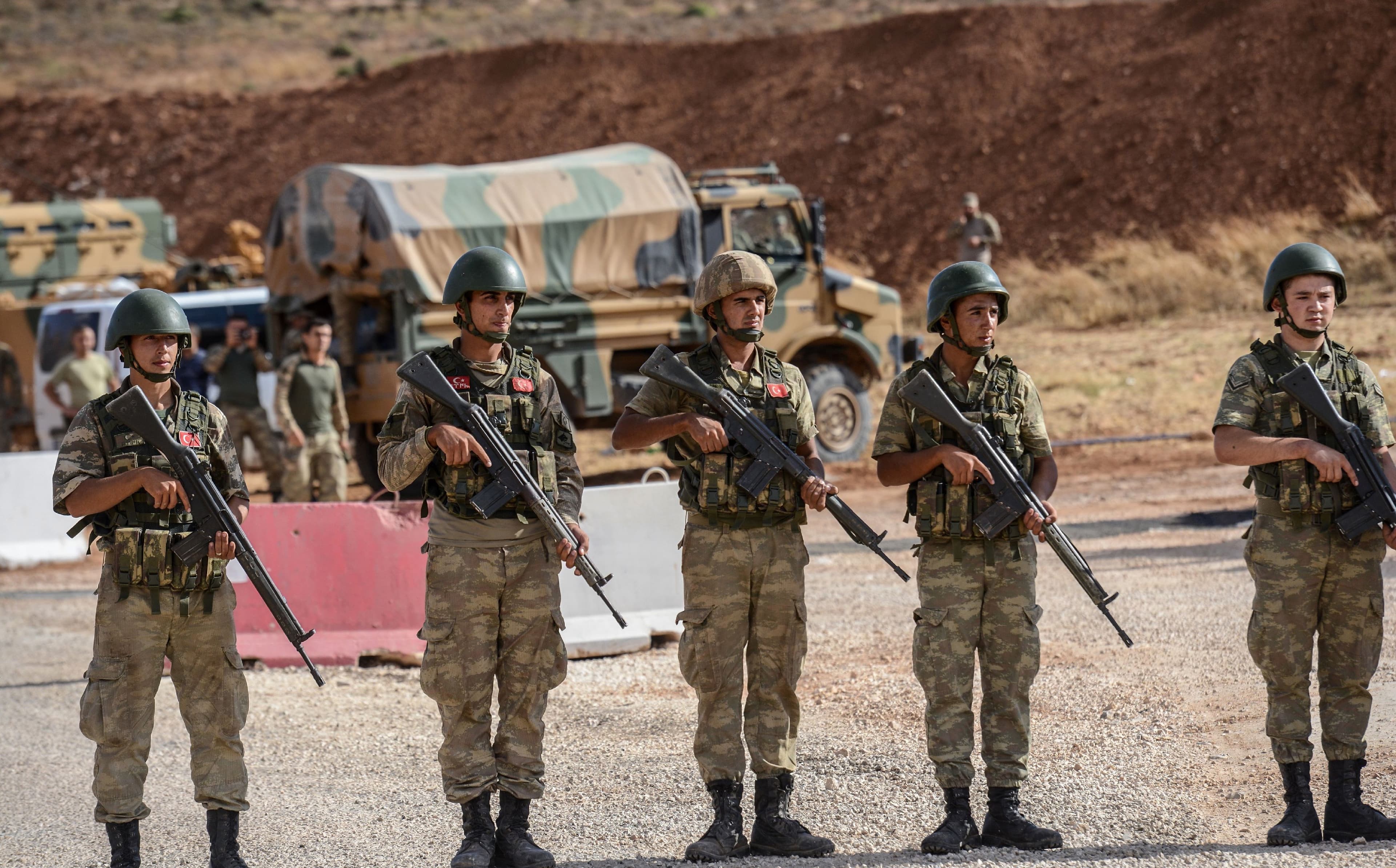 Turkish soldiers stand near armoured vehicles near the Turkey-Syria border. Photo: Ilyas Akengin / AFP