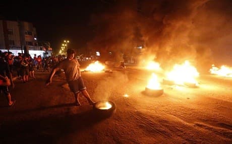 A demonstrator burns tyres during an ongoing protest against unemployment and high cost of living in the southern Iraqi city of Basra during the night of July 12, 2018. Photo: Haidar Mohammed Ali | AFP