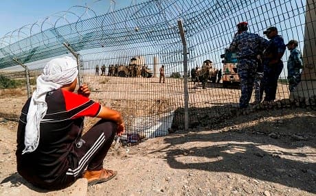 People in Basra say they are fenced out of their province's lucrative oil industry. A protester sits outside the al-Qurnah oil fields in the province on Saturday. Photo: Haidar Mohammed Ali/AFP