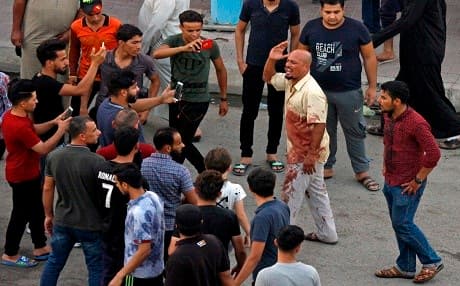 Iraqi demonstrators use cell phones to film protests in the central shrine city of Najaf on July 14, 2018. Photo: Haidar Hamdani | AFP