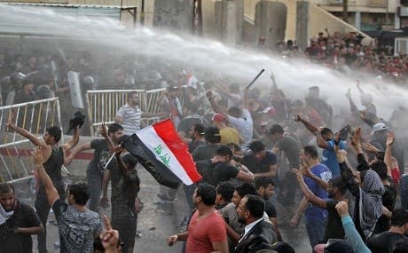 Iraqi protesters chant slogans and wave national flags are being sprayed with water cannon by security forces during clashes at a demonstration against unemployment and a lack of basic services in the capital Baghdad's Tahrir Square on July 20, 2018. Photo: Ahmad al-Rubaye / AFP 