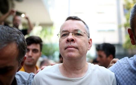 Pastor Andrew Brunson is escorted by Turkish plain clothes police as he arrives at his home on Wednesday where he will be kept under house arrest. Photo: AFP