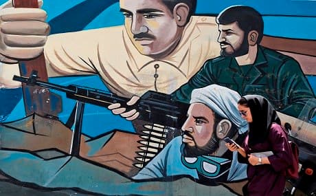 A woman walks past a graffiti mural depicting scenes of fighters painted along Palestine Square in the Iranian capital Tehran on July 24, 2018. File photo: Atta Kenare / AFP 