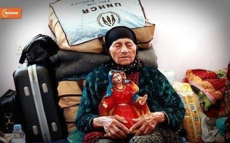 An elderly Christian woman made homeless by ISIS attacks on the minority in Iraq in 2014 sits with her belongings in the Kurdistan Region. Photo: Rudaw 
