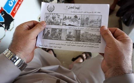 A Syrian man holds a leaflet stamped with the government forces' seal and dropped by helicopters flying over the city of Saraqibon August 9, 2018 reading in Arabic: "Which do you prefer? This was Syria before terrorism and its militiamen, and this is what armed terrorism has one to Syria and its people. The fate of your family, children, and future depend on your decision. Quickly join the local reconciliations to return the smile and guarantee the future." Photo: Omar Haj Kadour | AFP