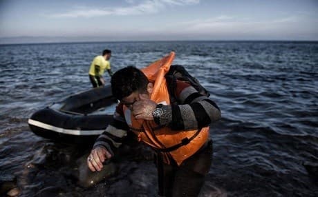 A man hides his face as refugees and migrants arrive on the Greek island of Lesbos after crossing the Aegean Sea from Turkey on November 11, 2015. File photo: AFP
