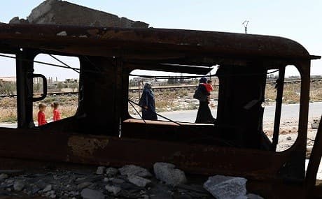 Syrian civilians are seen through a burned vehicle enter the Abu Duhur crossing on the eastern edge of Idlib province, August 20, 2018. Photo: George Ourfalian / AFP
