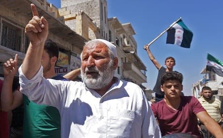 Syrians chant slogans and wave flags of the opposition as they protest against the regime and its ally Russia, in Binnish in Syria's rebel-held northern Idlib province on August 31, 2018. Photo: Muhammad Haj Kadour | AFP