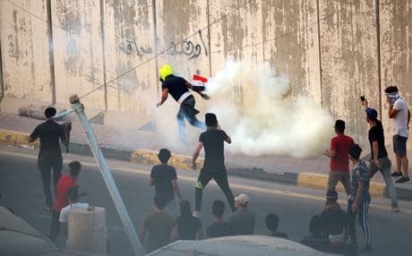 An Iraqi protester runs to throw a tear gas canister fired by Iraqi forces during a protest following the funeral of a man on September 4, 2018, that family and human rights activists claim was killed by bullet shots during the previous day. Photo: Haidar Mohammed Ali/AFP