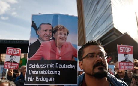 A demonstrator holds a poster showing German Chancellor Angela Merkel and Turkish President Recep Tayyip Erdogan and reading "Stop German support for Erdogan" on the sidelines of a state visit of the Turkish President to Berlin on September 28, 2018. Photo: Odd Andersen/AFP