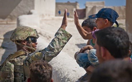 A US soldier high-fives a child while on patrol in Manbij. Photo: Staff Sgt. Timothy R. Koster/US Army