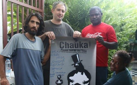Behrouz Boochani (L) poses with a poster advertising the documentary he filmed in Australia’s Manus Regional Processing Centre. Photo: Behrouz Boochani/Facebook