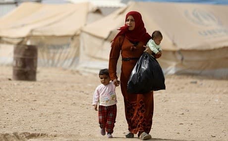 A displaced Syrian woman from Deir ez-Zor walks with her children in a camp for displaced people near Areesha, Hasaka province on October 8, 2018. Photo: Delil Souleiman/AFP
