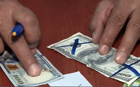 A person in the Kurdistan Region uses a marker to detect counterfeit bills. File photo: Rudaw