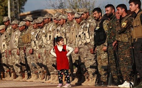 Qamishli, Syria : A young girl stands in front of fighters from the Syrian Democratic Forces (SDF) as they attend the funeral of a fellow fighter killed in the town of Hajin during battles against the Islamic State (IS) group, in the Kurdish-controlled city of Qamishly in northeastern Syria, on December 3, 2018. / AFP / Delil SOULEIMAN