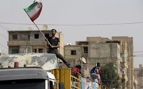A Syrian man waves an Iranian flag as a convoy carrying aid provided by Iran arrives in Deir ez-Zor in September 2017. File photo: Louai Beshara/AFP/Getty Images