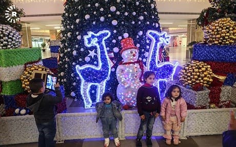 Children pose for photos in front of a Christmas display in Sulaimani. Photo: Sartip Othman/AFP