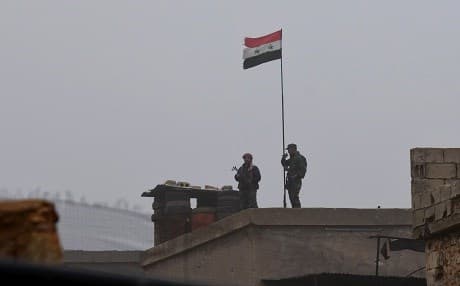 The Syrian national flag flies over a building south of Manbij on December 30, 2018. Photo: AFP
