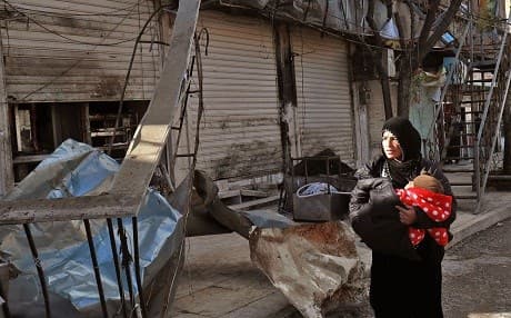 A Syrian woman walks past the site a suicide attack targeting US-led coalition forces in the flashpoint northern Syrian city of Manbij which killed four US serviceman the previous day on January 17, 2019. Photo: Delil Souleiman/AFP