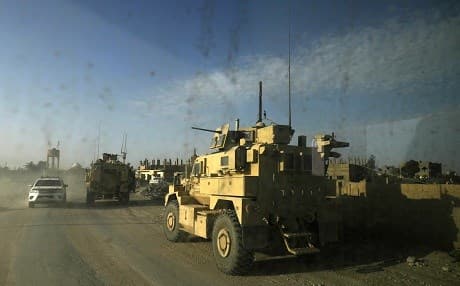 A picture taken from inside a car shows US military vehicles driving through the Syrian village of Baghouz in the countryside of the eastern Deir ez-Zor province on January 26, 2019. Photo: Delil Souleiman/AFP