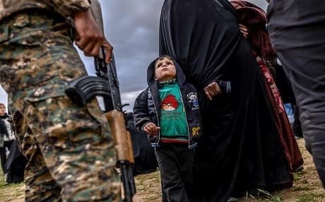 A young child looks at a member of the SDF after leaving ISIS's last holdout of Baghouz, Syria, on February 27, 2019. Photo: Bulent Kilic | AFP