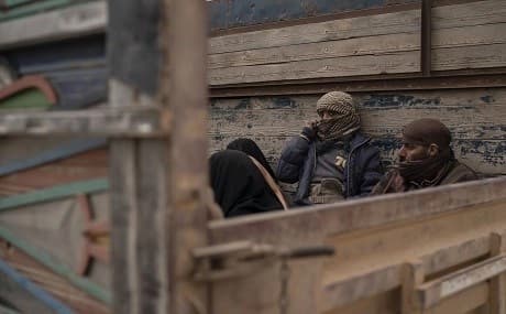 Men and women sit in the back of a truck as they wait to be screened by US-backed Syrian Democratic Forces (SDF) after being evacuated from the last territory held by Islamic State militants, in the desert outside Baghouz, Syria, Wednesday, February 27, 2019. Photo: Felipe Dana / AP
