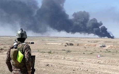 An Iraqi soldier looks at smoke billowing from an oil field in Saladin province in March 2015. File photo: AFP