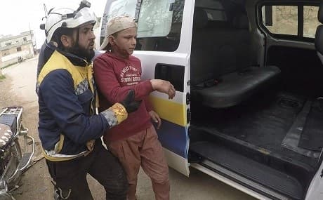 A civil defense worker helps a child after shelling at a street in Nairab, Idlib, northwest Syria, April 7, 2019. Photo: Syrian Civil Defense White Helmets / AP 