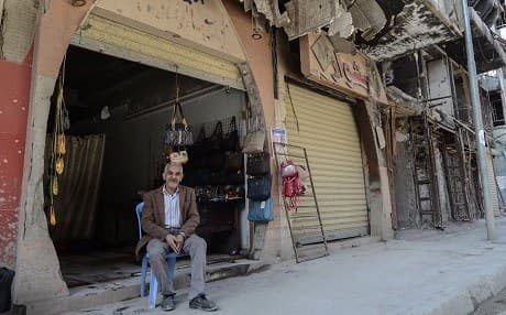 A man sits in front of a clothing shop under a damaged building in a neighbourhood of the old city of Mosul on April 21, 2019. Photo: Zaid al-Obeidi/AFP