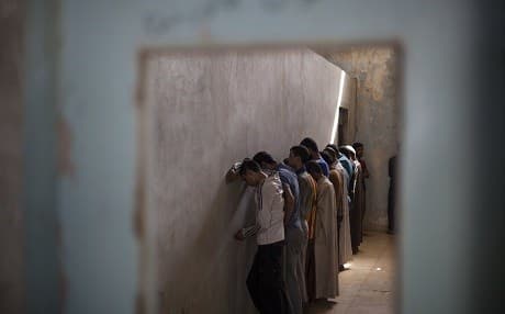 Displaced men from Hawija face a wall ahead of being screened by security officers for association with ISIS in Dibis, Iraq on October 3, 2017. Iraqi courts have sentenced hundreds to life in prison for membership in ISIS. File photo: Bram Janssen/AP
