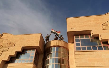 Iraqi forces raise a flag after retaking Bartella, outside Mosul, Iraq, October 21, 2016. Photo: Khalid Mohammed | AP
