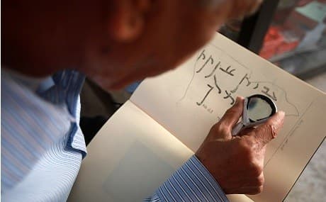 George Zaarour, a specialist in the Aramic language, uses a magnifying glass to decipher Aramaic script in the Syrian mountain village of Maalula, Damascus region, May 13, 2019. Photo: Louai Beshara / AFP 