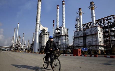 An Iranian oil worker rides his bicycle near an oil refinery south of the capital, Tehran, December 22, 2014. File photo: Vahid Salemi / AP