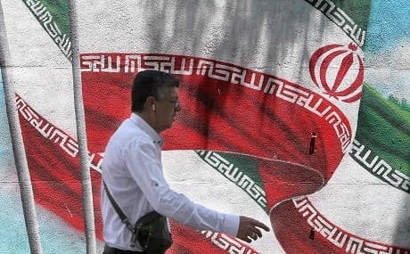 An Iranian man walks past a mural painted with the Iranian flag in Tehran, June 25, 2019. Photo: Atta Kenare / AFP 