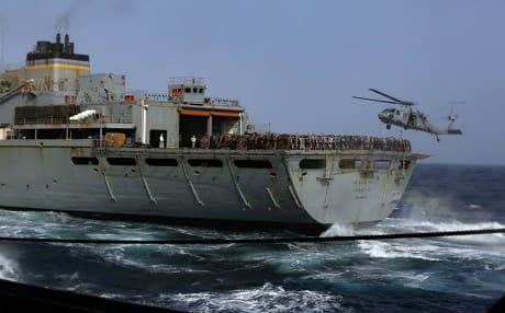 An MH-60S Sea Hawk helicopter receives cargo as the fast combat support ship USNS Arctic sails alongside the Nimitz-class aircraft carrier USS Abraham Lincoln during a replenishment-at-sea on July 1, 2019. Photo: Spc. Tristan Kyle Labuguen | US Navy