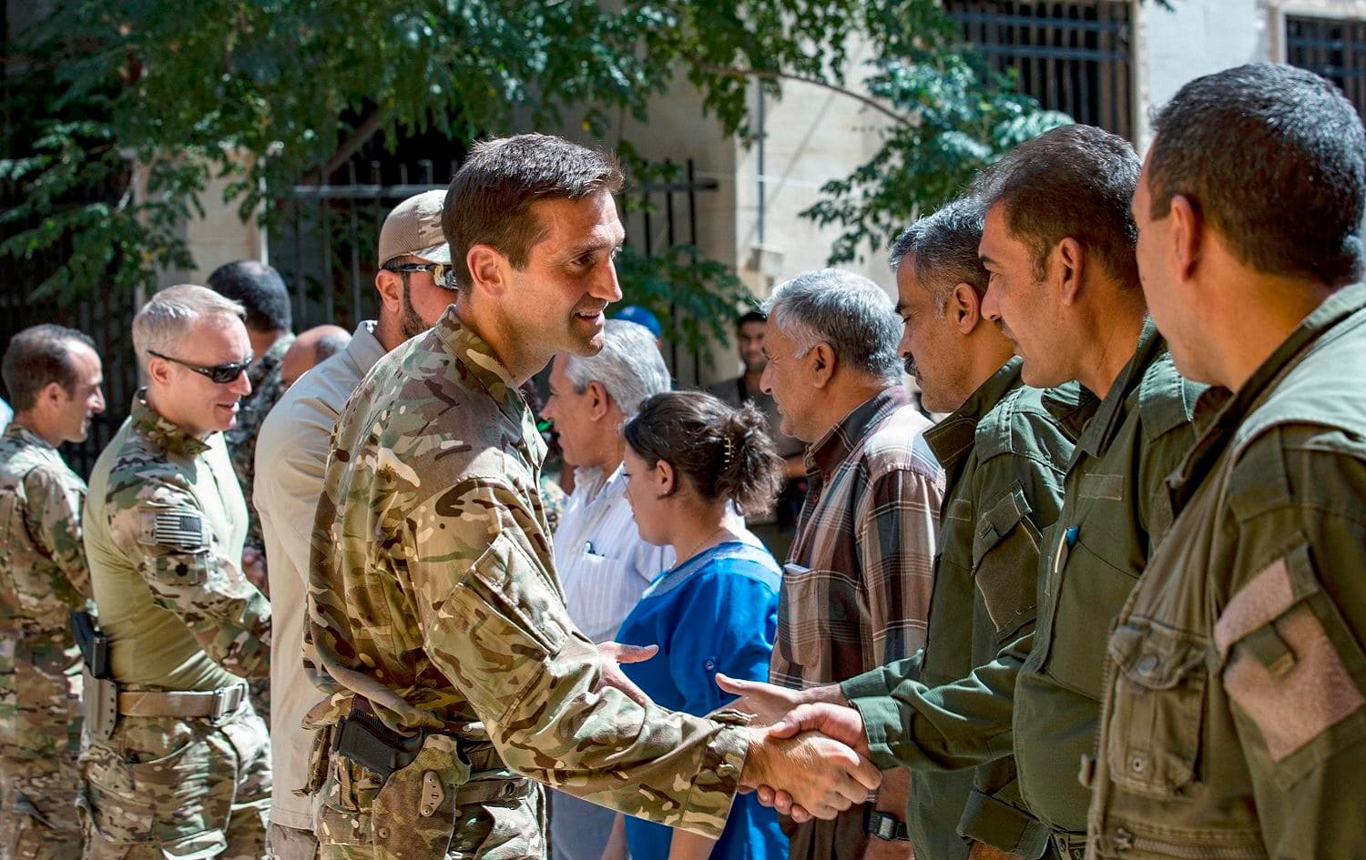 Members of the US-led coalition forces shake hands with local forces from the Tal Abyad military council in the northern Syrian town of Tal Abyad, September 15, 2019. Photo: Delil Souleiman / AFP 