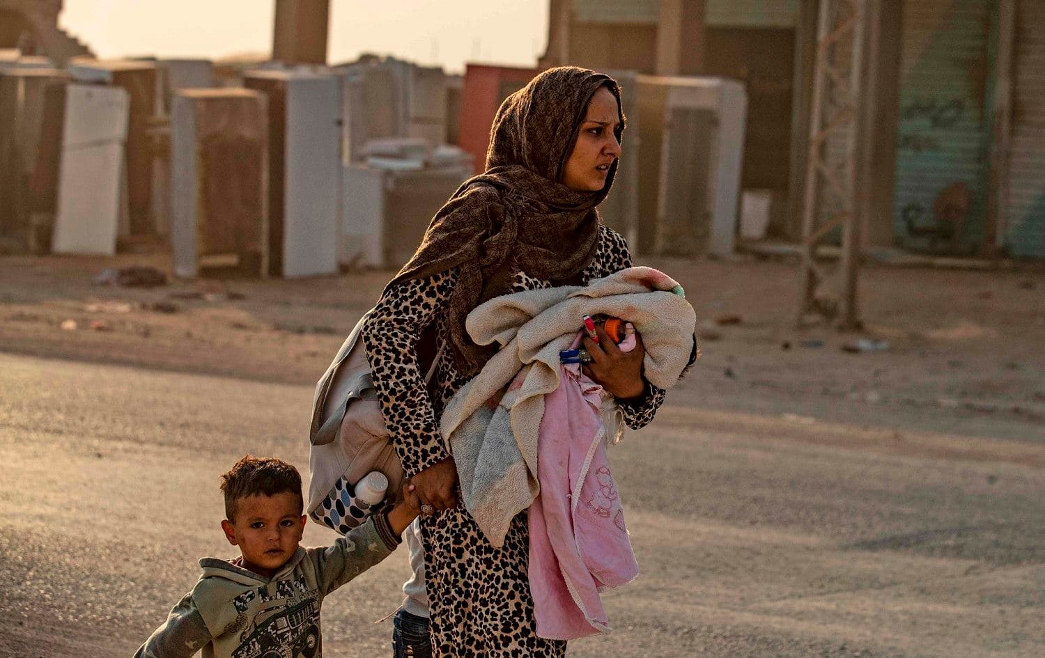 A woman flees with her children amid Turkish bombardment on Syria's northeastern town of Ras al-Ain in the Hasaka province along the Turkish border, October 9, 2019. File photo: Delil Souleiman / AFP 